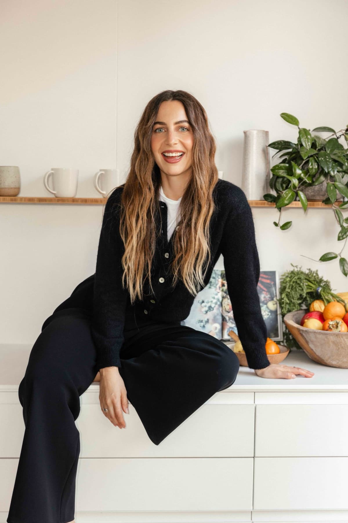 Meghan Swidler sitting on a white kitchen counter, laughing